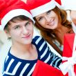 Young happy couple in Christmas hats standing together and holdi