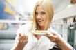 Portrait of young pretty smiling woman eating cake at shopping m