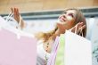 Photo of young joyful woman with shopping bags on the background