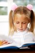 Image of smart child reading interesting book in classroom