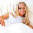 Young blond woman enjoying a sunny morning in bed