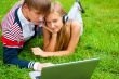 Happy young couple using laptop while lying on grass