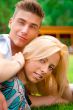 Portrait of beautiful young couple sitting on ground in park rel