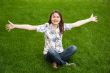 Full length of pretty young woman resting on grass and smiling
