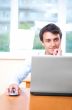 A young man sitting in front of a laptop in his office