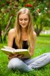 Beautiful female student outdoors with a book at campus park