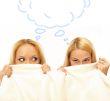 Two women whispering and amazing under blanket