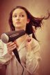 Beautiful woman drying her hair with hairdryer