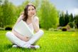 Young woman with laptop sitting on green grass