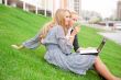 Portrait of two smiling women using laptop on a green meadow at 