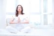 Young woman meditating with closed eyes in bright bedroom sittin
