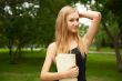 Beautiful female student outdoors with a book at campus park