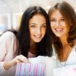 Two excited shopping woman resting on bench at shopping mall loo