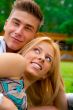 Portrait of beautiful young couple sitting on ground in park rel
