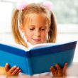 Image of smart child reading interesting book in classroom