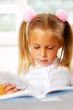Image of smart child reading interesting book in classroom