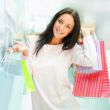 Photo of young joyful woman with shopping bags on the background
