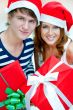 Young happy couple in Christmas hats standing together and holdi