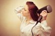 Beautiful woman drying her hair with hairdryer
