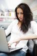 Portrait of a beautiful young woman working on laptop while sitt