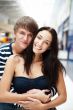 Portrait of young couple embracing at shopping mall and looking 