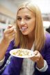 Closeup portrait of an attractive young woman eating fruit salad