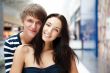Portrait of young couple embracing at shopping mall and looking 