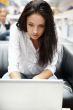 Portrait of a beautiful young woman working on laptop while sitt