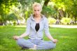Portrait of young woman meditating in pose of lotus on green gra
