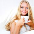 Smiling woman drinking a coffee lying on a bed at home or hotel.
