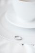 Closeup photo of proposal ring on white plate of coffee cup and 