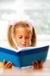 Image of smart child reading interesting book in classroom