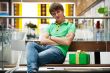 Portrait of young man inside shopping mall with gift box sitting