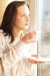Portrait of cosy young girl standing near a window at home