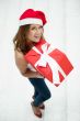 Young happy girl in Christmas hat. Standing indoors and holding 