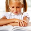 Image of smart child reading interesting book in classroom