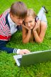 Happy young couple using laptop while lying on grass