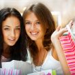 Two excited shopping woman resting on bench at shopping mall loo