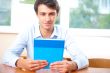 Portrait of a young handsome man with a book indoors