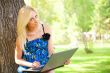 Portrait of a pretty student woman leaning on the tree trunk on 