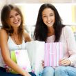 Two excited shopping woman resting on bench at shopping mall loo
