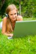 A smiling young girl with laptop outdoors listening music by hea