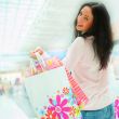 Photo of young joyful woman with shopping bags on the background