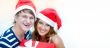 Young happy couple in Christmas hats standing together and holdi