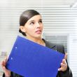 A portrait of a young business woman in an office with documents