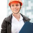 Young architect-woman wearing a protective helmet standing on th