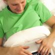 Attractive man relaxing in bed. White silk linen. Working by is 
