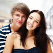 Portrait of young couple embracing at shopping mall and looking 