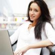 Portrait of a beautiful young woman working on laptop while sitt