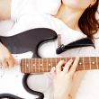 Teen girl holding a guitar like a rock star and enjoying playing